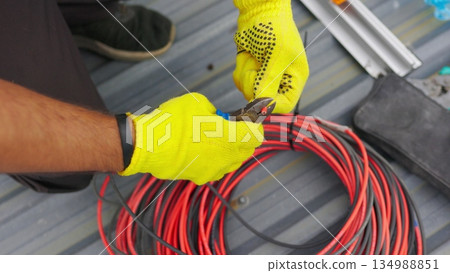 Electrician technician worker with wire stripper plier prepares the electric cable in electrical system. Electrician installing wires. A professional electrician removes electrical insulation. Electrician technician worker with wire stripper plier prepares the electric cable in electrical system. Electrician installing wires. A professional electrician removes electrical insulation. 134988851