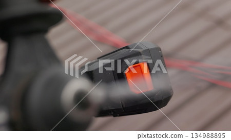 Unrecognizable construction worker on a construction site, holding a work tool, drill or power tools in the hands. Concept: construction and repair. Screensaver for a construction company. 134988895