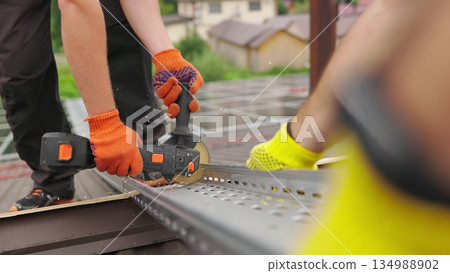 Male hand cuts off pieces of pipe with angle grinder. Cutting of a steel with splashes of sparks at construction site. Slow motion of construction worker cutting steel beam. Male hand cuts off pieces of pipe with angle grinder. Cutting of a steel with splashes of sparks at construction site. Slow motion of construction worker cutting steel beam. 134988902