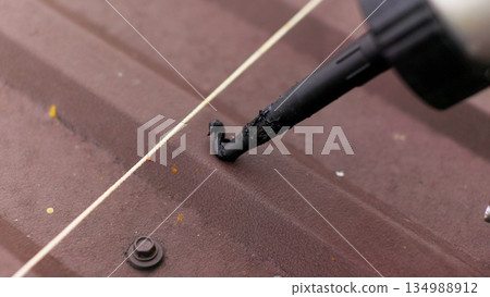 Close up of applying sealant on the roof. Carpenter repairing cabin roof of boat sealing leaks with mastic waterproof sealant Close up of applying sealant on the roof. Carpenter repairing cabin roof of boat sealing leaks with mastic waterproof sealant 134988912