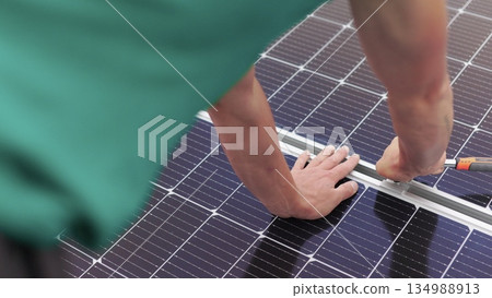 Installation, Connection and mounting of solar panels. Workers fasten solar panels. Technicians installing solar panels on metal stand. Workers installing PV solar panels on the roof of a house. 134988913