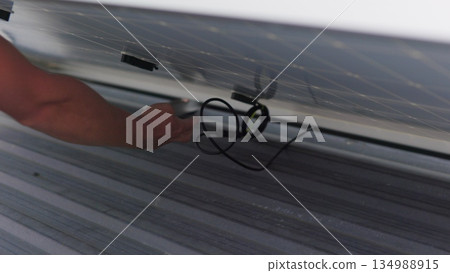 Solar technician installing solar panels on roof. Concept of Ecological Renewable Energy at Home. Technicians installing PV solar panels on rooftop of house during bright sunlight. Slow motion Solar technician installing solar panels on roof. Concept of Ecological Renewable Energy at Home. Technicians installing PV solar panels on rooftop of house during bright sunlight. Slow motion 134988915