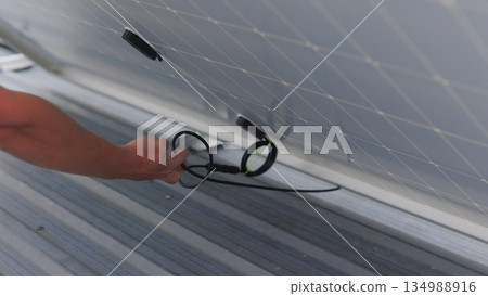Solar technician installing solar panels on roof. Concept of Ecological Renewable Energy at Home. Technicians installing PV solar panels on rooftop of house during bright sunlight. Slow motion Solar technician installing solar panels on roof. Concept of Ecological Renewable Energy at Home. Technicians installing PV solar panels on rooftop of house during bright sunlight. Slow motion 134988916
