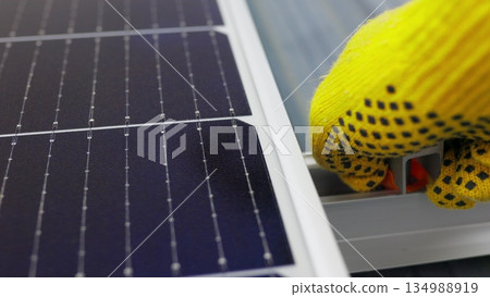 Mounting solar panel, installing solar panels on the roof of the house. Connection of solar panels. Close up of worker installing and working on maintenance of photovoltaic panel system installed Mounting solar panel, installing solar panels on the roof of the house. Connection of solar panels. Close up of worker installing and working on maintenance of photovoltaic panel system installed 134988919