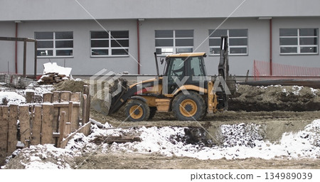 The bulldozer works on a construction site with sand, side view. New Big Tractor, a bulldozer on wheels on a sandy road on a construction site levels the site for the construction of real estate. The bulldozer works on a construction site with sand, side view. New Big Tractor, a bulldozer on wheels on a sandy road on a construction site levels the site for the construction of real estate. 134989039