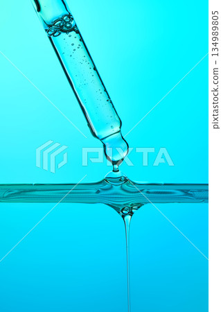 Pipette dispensing clear blue liquid drop into serum Pipette dispensing clear blue liquid drop into serum 134989805