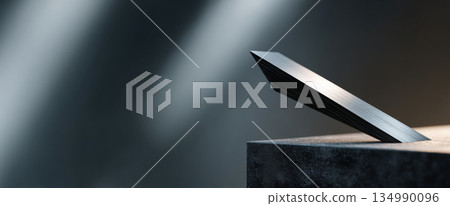 Close-up of a sleek metallic object balanced on a textured dark surface with dramatic lighting and blurred background 134990096