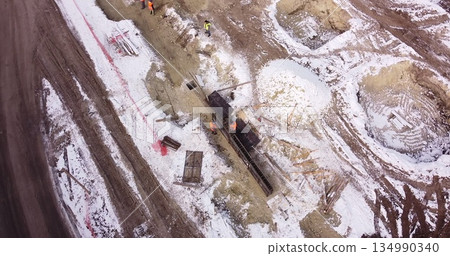 Engineers work with metal constructions while building a house. Aerial Flight Over a New Constructions Development Site. Top Down View at Contractors in Safety Hats Engineers work with metal constructions while building a house. Aerial Flight Over a New Constructions Development Site. Top Down View at Contractors in Safety Hats 134990340