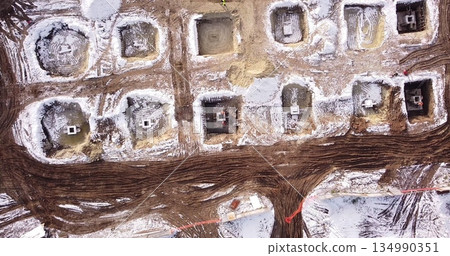Top ascending aerial view of a foundation of a frame house in winter and working laborers. Snowy day. 134990351
