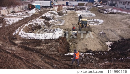 Aerial view of heavy machinery, tractor transporting land, construction preparation. The skating rink compacts the ground. Start of construction of the building flick 134990356