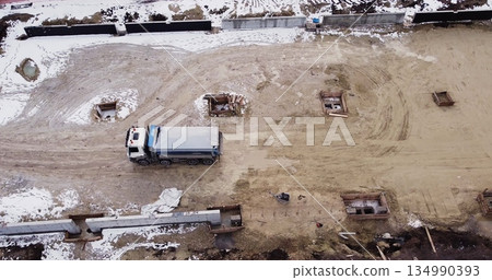 Aerial view of heavy machinery, Articulated truck moving dirt on a new road construction site, heavy equipment top down footage of dump truck. Aerial view of heavy machinery, Articulated truck moving dirt on a new road construction site, heavy equipment top down footage of dump truck. 134990393
