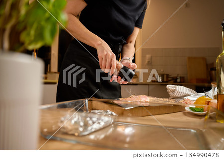 Seasoning raw chicken breast with salt on kitchen counter Seasoning raw chicken breast with salt on kitchen counter 134990478
