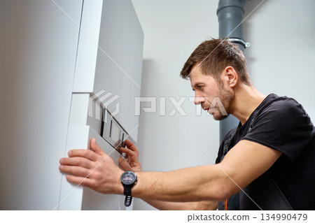 Man adjusting control panel of heat pump during installation Man adjusting control panel of heat pump during installation 134990479
