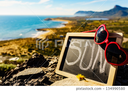 Black board with word sun against sea coast Black board with word sun against sea coast 134990580