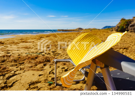 Yellow straw hat on sandy beach Yellow straw hat on sandy beach 134990581