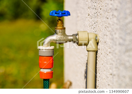 Garden tap with hosepipe attached. Garden tap with hosepipe attached. 134990607