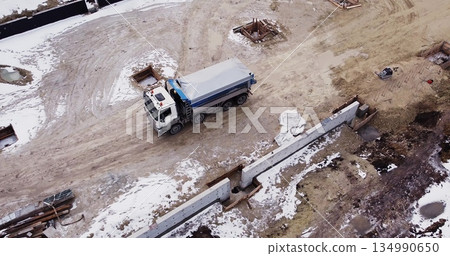 Aerial view of heavy machinery, Articulated truck moving dirt on a new road construction site, heavy equipment top down footage of dump truck. Aerial view of heavy machinery, Articulated truck moving dirt on a new road construction site, heavy equipment top down footage of dump truck. 134990650