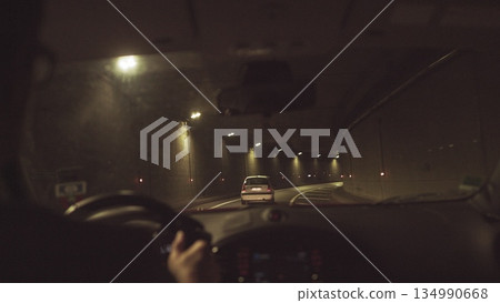 A man rides in a car through a lighted tunnel. Beautiful frame shooting through from the car A man rides in a car through a lighted tunnel. Beautiful frame shooting through from the car 134990668
