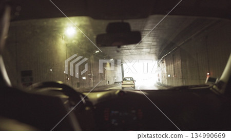 A man rides in a car through a lighted tunnel. Beautiful frame shooting through from the car A man rides in a car through a lighted tunnel. Beautiful frame shooting through from the car 134990669