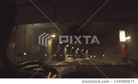 A man rides in a car through a lighted tunnel. Beautiful frame shooting through from the car A man rides in a car through a lighted tunnel. Beautiful frame shooting through from the car 134990671