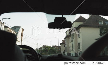 A man rides in a car at sunset on the streets of a modern city. The navigator is included. Shooting from the back seat. Passes under the bridge and the train goes from above. 134990673