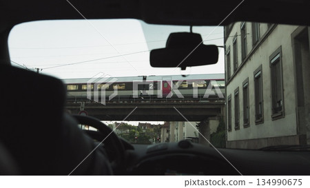 A man rides in a car at sunset on the streets of a modern city. The navigator is included. Shooting from the back seat. Passes under the bridge and the train goes from above. 134990675