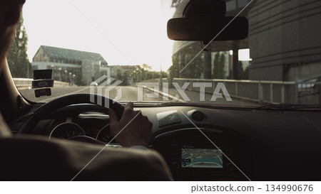 A man rides in a car at sunset on the streets of a modern city. The navigator is included. Shooting from the back seat. France,Strasbourg. A man rides in a car at sunset on the streets of a modern city. The navigator is included. Shooting from the back seat. France,Strasbourg. 134990676