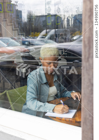 work online. African American young woman is sitting in coffee shop and working on laptop. work online. African American young woman is sitting in coffee shop and working on laptop. 134990756