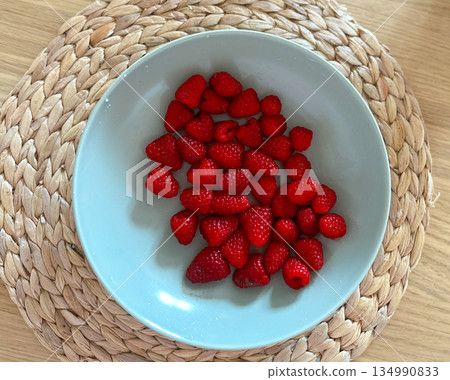 Fresh raspberries in bowl on table viewed from above. Healthy food concept, natural sweetness, seasonal fruit and clean eating 134990833