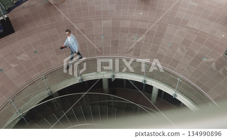 Middle-aged businessman in luxurious clothes, walking around the office in a financial district in the capital city, a successful proud male CEO, smiling during cell phone messages. Shooting from 134990896