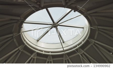 Top view on Structural glass facade curving roof of office building. Modern and contemporary architectural fiction with glass steel column. Aerial shot of glass dome construction. Top view on Structural glass facade curving roof of office building. Modern and contemporary architectural fiction with glass steel column. Aerial shot of glass dome construction. 134990902