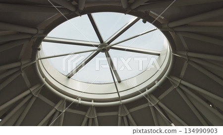 Top view on Structural glass facade curving roof of office building. Modern and contemporary architectural fiction with glass steel column. Aerial shot of glass dome construction. Top view on Structural glass facade curving roof of office building. Modern and contemporary architectural fiction with glass steel column. Aerial shot of glass dome construction. 134990903