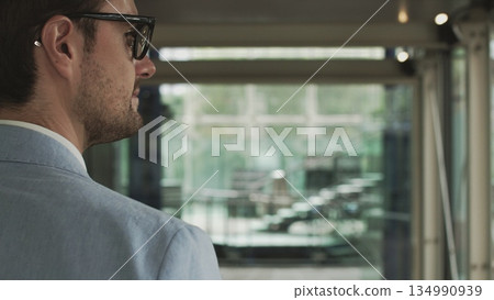 A young businessman, an employee of a large company walks around a modern beautiful office and greets, waves his hand. Shooting with hands close up. The concept of a successful employee A young businessman, an employee of a large company walks around a modern beautiful office and greets, waves his hand. Shooting with hands close up. The concept of a successful employee 134990939