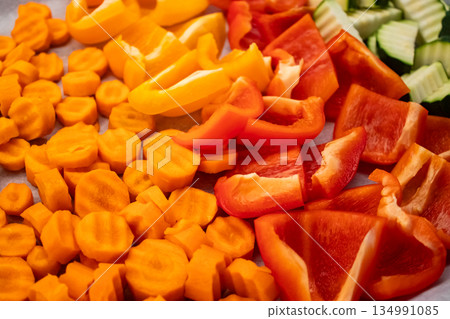 Sliced carrots, bell peppers and zucchinis creating colorful wallpaper on baking tray Sliced carrots, bell peppers and zucchinis creating colorful wallpaper on baking tray 134991085