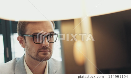 Male eyes in eyeglasses in front of laptop. Coder, programmer or developer using laptop. Close up of glasses. 134991194