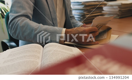 Serious young businessman checking corporate paperwork correspondence sitting at home office desk. Male entrepreneur reading documents, analyzing financial papers, preparing audit report at workplace Serious young businessman checking corporate paperwork correspondence sitting at home office desk. Male entrepreneur reading documents, analyzing financial papers, preparing audit report at workplace 134991204