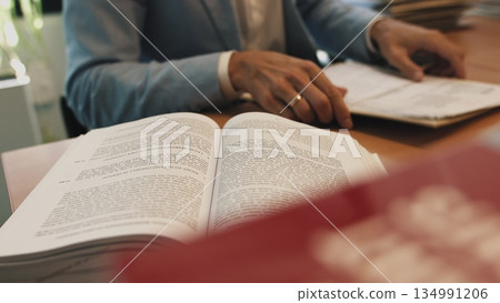 Serious young businessman checking corporate paperwork correspondence sitting at home office desk. Male entrepreneur reading documents, analyzing financial papers, preparing audit report at workplace 134991206