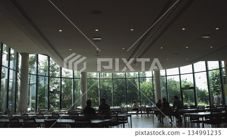 Large modern office space, people sitting at tables and relaxing. lunch. Large modern office space, people sitting at tables and relaxing. lunch. 134991235