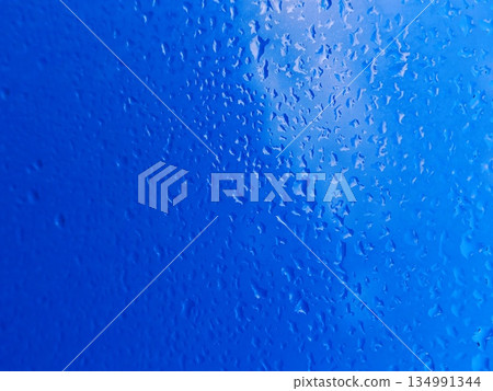 Water Droplets Background Texture. Close-up view of condensed water droplets running down blue surface creating refreshing abstract pattern. Water Droplets Background Texture. Close-up view of condensed water droplets running down blue surface creating refreshing abstract pattern. 134991344