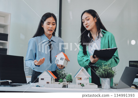 Professional real estate agents brainstorming house project while planning home investment with architectural model and documents Professional real estate agents brainstorming house project while planning home investment with architectural model and documents 134991393