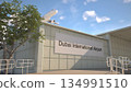 Dubai International Airport entrance sign and airplane passing above on a summer day, Dubai, United Arab Emirates 3D rendering 134991510