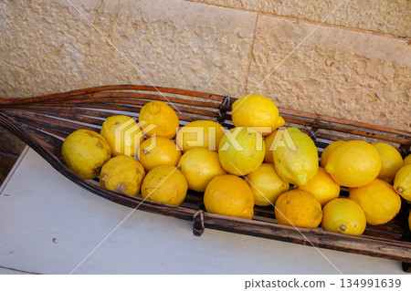 Many fresh yellow lemons in wooden bowl close up Many fresh yellow lemons in wooden bowl close up 134991639