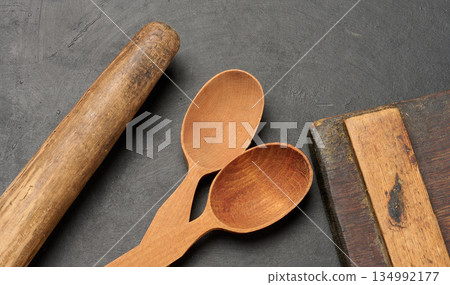 Wooden spoons, cutting board and rolling pin on a dark surface Wooden spoons, cutting board and rolling pin on a dark surface 134992177