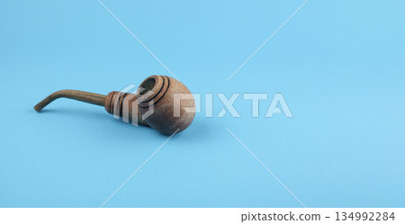 Wooden smoking pipe on a blue background Wooden smoking pipe on a blue background 134992284