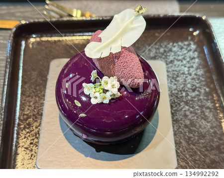 Elegant purple dessert with flower on black plate 134992292