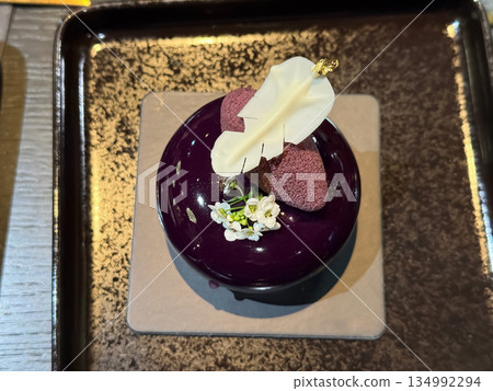 Elegant purple dessert with flower on black plate 134992294