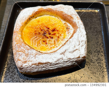 Cream puff pastry sprinkled with powdered sugar on black plate. 134992301