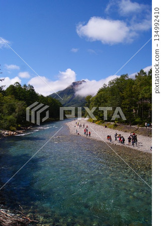 A panoramic view of the riverside and mountains where people gather 134992410