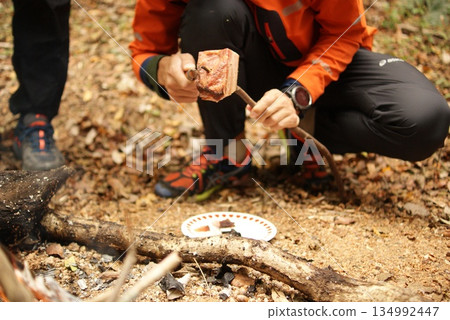 Cooking thick cuts of meat on skewers over a forest bonfire 134992447