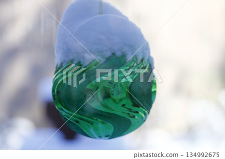Large, Snow-Covered Christmas Ornament on a Outdoor Tree 134992675